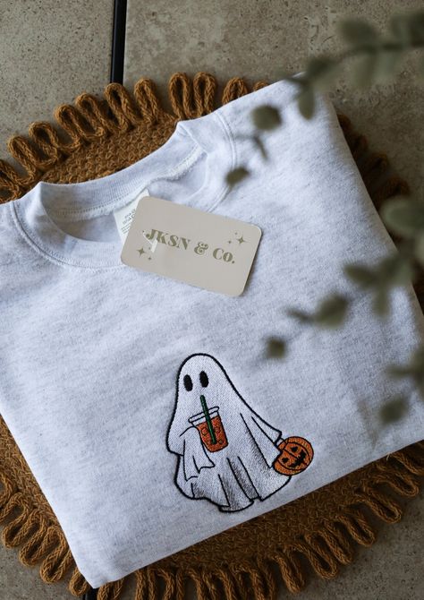 Get ready for the spooky season with our Embroidered Iced Coffee Ghost Crewneck! This cute and cozy sweatshirt features an adorable ghost enjoying an iced coffee, perfect for Halloween and fall fashion lovers. Why You'll Love It: Unique Design: Custom embroidered ghost with iced coffee, exclusively designed for this crewneck!  High-Quality Material: Made from soft, durable fabric to keep you comfortable all autumn long!  Perfect for Fall: Ideal for Halloween parties, pumpkin patch visits, or jus Fall Sweater Designs, Cute Halloween Crewneck, Halloween Embroidery Designs Sweater, Halloween Clothes Aesthetic, Fall Embroidered Sweatshirts, Embroidered Clothes Ideas, Sweatshirts Ideas, Autumn Sweatshirts, Ghost With Coffee