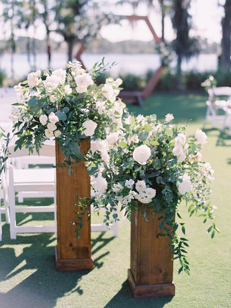 White and Green Floral Altar pieces in a garden style atop of natural wood stands. Wedding Aisle Columns, Wedding Ceremony Column Flowers, Floral Stand Wedding Ceremony, Nature Wedding Ceremony Decor, Ceremony Arrangements On Pedestals, Free Standing Wedding Ceremony Flowers, Floral Arrangements On Pedestals, Pedestal Flowers Wedding Ceremony, Aisle Entry Flowers