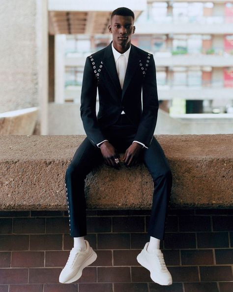 Black man wearing Alexander McQueen black suit with white shirt and white sneakers. This image was included in the article: Fire Kicks: The 10 Hottest Fashion Sneaker Brands In 2023, on MensFlair.com Jimin Outfit, Man Styling, Black Men Suits, Prom Blazers, Tuxedo Coat, Sneaker Trends, Alexander Mcqueen Fashion, Sarah Burton, Dress Better