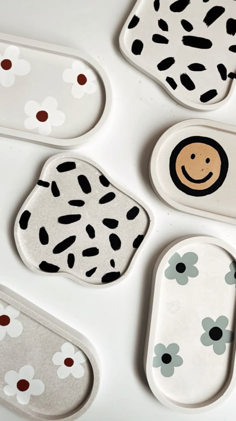 A collection of hand crafted hand painted floral and smiley trays or jewelry dishes. Key Tray Ideas, Pottery Dish Ideas, Jesmonite Painting, Clay Tray Painting Ideas, Jewelry Dish Diy, Ceramics Tray, Tray Painting, Jewelry Tray Painting Ideas, Diy Clay Tray