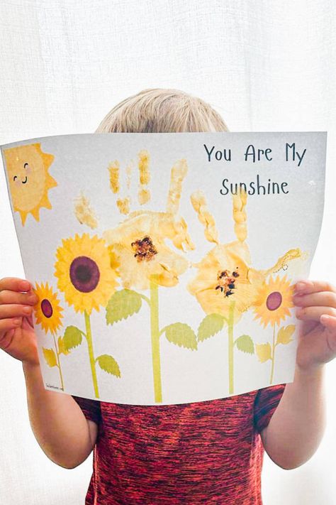 This free printable you are my sunshine handprint craft for kids is so sweet and a really easy craft! The child’s little fingers as sunflower petals and fingerprints for the seeds create a beautiful keepsake. I love the bright colors that this printable has and you could even include a package of sunflower seeds if you were making this as a gift! S Is For Handprint Craft, Handprint Weather Crafts, Hand Print Art Preschool, Handprint Tractor Craft, You Are My Sunshine Handprint Craft, Fall Craft Handprint, Yellow Handprint Craft, You Are My Sunshine Footprint Art, You Are My Sunshine Handprint Art