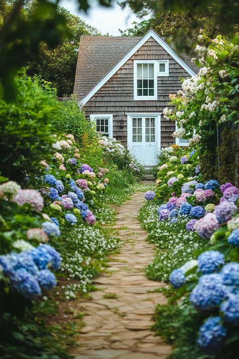 Garden path lined with lush blossoming flowers leading to a charming upkept cottage house in clapboard cladding and white windows. Discover the perfect dream cottage houses with cozy interiors, charming exteriors, and enchanting gardens. Brick Cottage, Woodland Cottage, Stone Chimney, Forest Cottage, Countryside Cottage, Brick Chimney, Stone Cottages, Small Cottage Homes, Lakeside Living