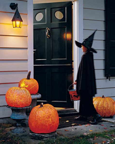 A front door tempts trick-or-treaters with a collection of eerie spiderwebs and a tarantula shining brightly. Martha Stewart Halloween Decorations, Birthday Streamers, Martha Stewart Halloween, Carved Pumpkins, Urn Planters, Pumpkin Stencil, Halloween Displays, Creepy Halloween, Theme Party Decorations