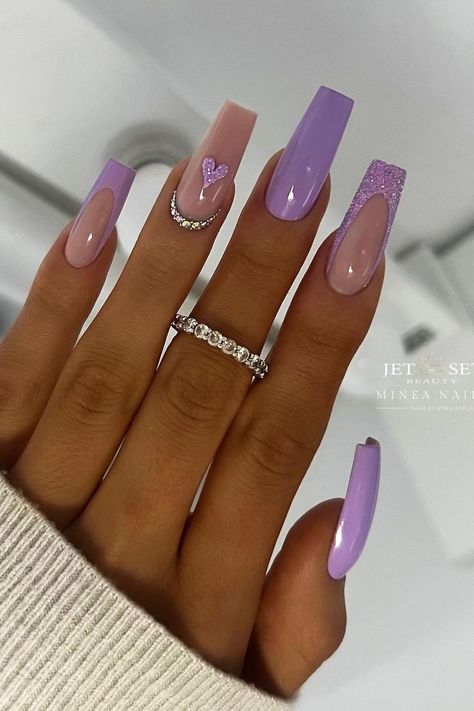 These luxurious, long coffin nails boast a lilac dream with subtle variations that speak of sophistication. A soft pastel shade sets the base for simplicity, enhanced by a delightful sparkle-embedded lavender on another for a touch of glamour. The minimalist chic design welcomes a tiny, glittering heart and a crescent of rhinestones, adding an understated yet captivating charm. Elegance meets whimsy in this perfectly curated purple palette. Simply enchanting!✨  // Photo Credit: Instagram @minea.nails Violet Purple Nails Acrylic, Nail Inspo Pastel Purple, Design On Purple Nails, Long Lilac Nails, Soft Purple Nails Designs, Long Acrylic Nails Coffin Purple, Glitter Lilac Nails, Lavender Acrylic Nails Design, Acrylic Nail Designs Purple Lavender