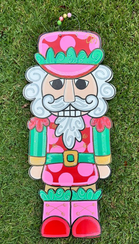 Retro Nutcracker door hanger!! too cute! perfect for your door decor for the holiday season!! Pink Nutcracker Door Hanger, Nutcracker Door Sign, Manger Door Hanger, Nutcracker Door Decorating Ideas, Nutcracker Canvas Painting, Christmas Painted Door Hangers, Pink Christmas Door Hanger, Nutcracker Door Decorations For School, Nutcracker Window Painting