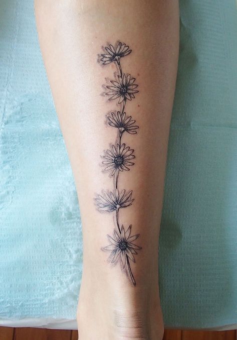 Daisy tattoo on the back of the calf Daisy Tattoo On Leg, Pretty Calf Tattoos For Women, Sunflower Tattoo On Calf, Daisy Leg Tattoos For Women, Calf Tats For Women, Sunflower Chain Tattoo, Daisy Foot Tattoos For Women, Daisy Chain Tattoo Arm, Daisy Leg Tattoo