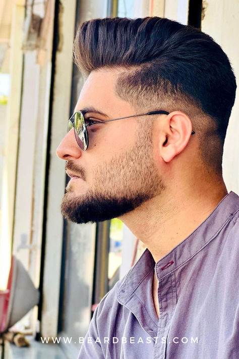 A stylish man with a well-groomed Balbo beard and a trendy fade haircut, showcasing a sharp and modern men's hairstyle. Wearing sunglasses and a casual shirt, he exudes confidence and contemporary fashion sense. This image highlights the Balbo beard, a popular choice among beard styles for men, known for its clean lines and distinct shape. Ideal for those seeking inspiration for men's haircuts and beard styles, this visual captures the essence of current grooming trends. Balbo Beard, Beard Style For Men, Kohli Hairstyle, Popular Beard Styles, Virat Kohli Hairstyle, Beard Guide, Best Beard Styles, Beard Fade, Beard Style