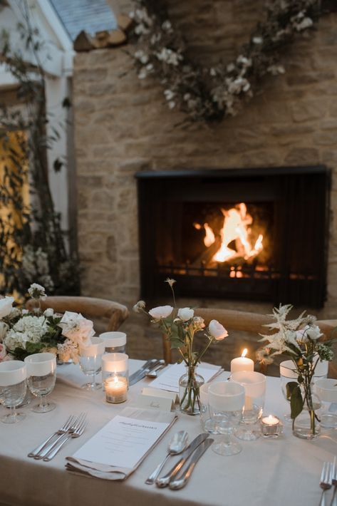 A fireplace glows beside a wedding table that is decorated in a festive manner Cosy Winter Wedding, Winter Wedding Uk, Cosy Wedding, Daylesford Farm, Bud Vase Centerpiece, Wedding Feast, Green Weddings, Vase Centerpiece, Cottage Wedding