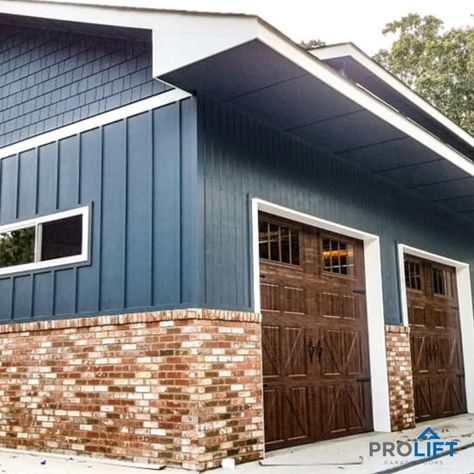 Detached garage with multi-colored brick with blue siding/shingles and faux wood carriage house garage doors by ProLift Garage Doors Multi Color Brick House Exterior, Blue House With Garage Doors, Blue House With Brown Garage Door, Blue House Brown Garage Door, Blue House Garage Door Color, Navy Siding With Brick, Blue Siding Red Brick, Multi Colored Brick Exterior, Blue House Exterior With Brick