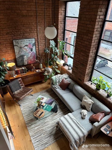 Old money, loft, apartment, vintage, retro, vibes, masculine, interior design, living room inspo, gray couch, grey sofa, glass coffee table, gray grey rug, leather chair, high cealing, unique wall art, plants in room, top down view, table decoration, shelf decoration, 1900s vibe, rich vibe, 80s, 90s, 70s, natural lighting Room Inspo Gray, Interior Design Open Floor Plan, Masculine Interior Design Living Room, Vintage Loft Apartment, Loft Living Room Ideas, Plants In Room, Loft Entrance, Contemporary Loft Design, Loft Art Studio