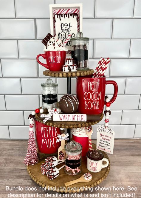 "This listing is for the Hot Cocoa Bar Bundle and includes: -Mini Red \"Cocoa\" Mug with mini wooden spoon (mug-top tier, spoon-bottom tier) -Hot Cocoa Bar sign (top tier, back center-may need small risers to make taller as shown in photos) -Set of 3 Empty Glass Jars (Marshmallows, Chocolate, Candy Canes- one on each tier-hand wash only-made with permanent vinyl-contents not included-jars will come empty) -Wooden Spoon with set of 3 mini marshmallows (mallows on top tier, spoon on bottom tier) - Hot Cocoa Tiered Tray, Cocoa Tiered Tray, Christmas Hot Chocolate Bar, Canes Decor, Tray Decor Christmas, Faux Food, Dessert Candles, Christmas Hot Chocolate, Christmas Decor Inspiration