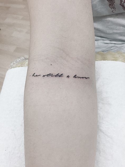 “be still & know” single needle tattoo Stillness Tattoo, Christian Word Tattoo Ideas, Dainty Bible Tattoos, Minimal Bible Tattoo, Be Still Arm Tattoo, Christian Script Tattoo, Be Still Tattoo With Flower, The Rest Is Still Unwritten Tattoo, Be Still Tattoos For Women