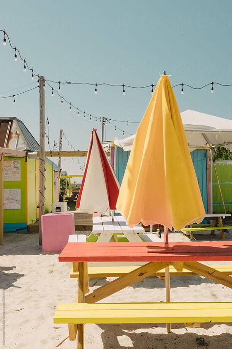 Colorful summer tourist location with empty picnic tables and beach umbrellas. Outdoors patio seating. Outdoor Picnic Table With Umbrella, Picnic Table Umbrella, Picnic Umbrella, Beach Seating, Nautical Patio, Vintage Beach Party, Colorful Picnic, Picnic Table With Umbrella, Sand House