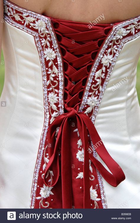 Download this stock image: The back of a bride's red and white wedding dress showing the lacing, decoration and bow. - B356EB from Alamy's library of millions of high resolution stock photos, illustrations and vectors. Wedding Dresses With Red Accents, Red And White Wedding Dress Lace, Maroon And White Wedding Dress, Red And White Ball Gown, White N Red Wedding Dress, Red Accent Wedding Dress, White And Burgundy Wedding Dress, Wedding Dress With Red, Wedding Dress With Red Accents