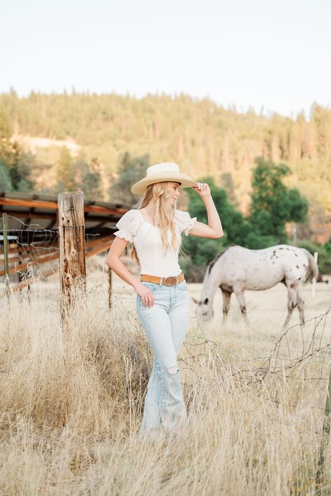 girl tipping cowgirl hat with horse in background Farm Senior Pictures, Horse Shoot, Cowgirl Photography, Sweet Personality, Cowgirl Pictures, Horse Photo, Graduation Photography Poses, Letterman Jackets, Cowgirl And Horse