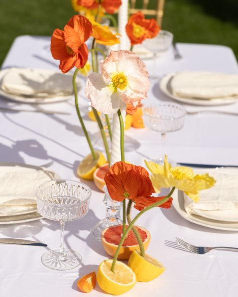 When @annapaulinephotography @stoddardfloralandco and I were designing this bridesmaids tablescape, we stumbled upon a floral design that had florals organically growing out of sunset colored fruit. The poppies were Anna’s favorite of the day and boy did they turn out incredibly beautiful! Do you like poppies in floral design? 😍 Photographer: @_ameysphotography Creative Director: @annapaulinephotography Planner: @bashboulevard Venue: @theantillamansion Florist: @stoddardfloralandco Hair... Poppies Table Setting, Flower Base Ideas Diy, Potted Plant Tablescape, Fruit Bachelorette Party, Fruit Decorations Wedding, Sunset Tablescape, Lemon Arrangements, Wedding Fruit Table, Citrus Table Decor