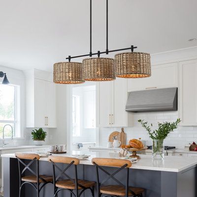 This farmhouse-style linear island chandelier light features matte black hardware and 3 drum shades which are meticulously hand-woven of natural rattan/wicker, making it a unique hanging pendant light for above the kitchen island and dining table or cafe bar. This collection can work with a variety of boho decors and even work in homes with coastal or farmhouse styling | Bay Isle Home™ Lannister 3 - Light Kitchen Island Drum Chandelier Metal in Brown | 10.4 H x 41 W x 11 D in | Wayfair Kitchen Island And Dining Table, Island And Dining Table, Farmhouse Chandelier Lighting, Lights Over Kitchen Island, Island Light Fixtures, Island Chandelier, Kitchen Chandelier, Light Kitchen Island, Dining Room Light Fixtures
