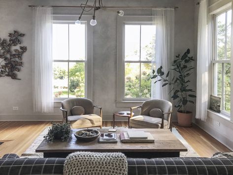 In a room with high ceilings, twin windows are flanked by foliage, both faux and alive. The shape and texture of a potted Ficus elastica’s leaves mimics a wall sculpture and adds to the sense of symmetry created by a pair of eBay armchairs. Photograph by Jersey Ice Cream Co. Jersey Ice Cream Co, Amazing Windows, White Molding, Coastal Living Rooms, Empty Room, Living Room Remodel, Vintage Sofa, Cool Beds, Vintage Farmhouse