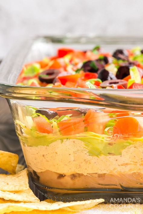 This family favorite taco dip uses refried beans, guacamole, sour cream, cream cheese, taco seasoning and plenty of crunchy toppings. The perfect party dip! Nacho Bean Dip, Easy Taco Dip With Refried Beans, Taco Dip With Cream Cheese Refried Beans, Taco Dip With Refried Beans, Taco Bean Dip, Taco Salad Dip, Cream Cheese Bean Dip, Cream Cheese Taco Dip, Crunchy Toppings