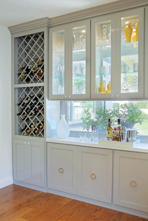 Gorgeous kitchen bar features stacked cross cut built in wine racks placed next to see through cabinets, with view to backyard, over a framed window backsplash and gray cabinets adorned with ring pulls. Window Cupboards, Split Kitchen, Sunset Villa, Kitchen Window Bar, Kitchen Pass Through, Built In Wine Rack, Divider Ideas, Window Bars, Kitchen Updates