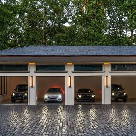 This photo showcases a luxury garage with an elegant design, housing high-end vehicles. The garage features clean, modern architecture with well-lit interiors and large glass-panel garage doors. The lighting adds a warm glow to the building, creating a sophisticated ambiance. The cars visible include luxury models such as a Mercedes-Benz and possibly a Bentley or similar vehicles, emphasizing exclusivity and style. The driveway is made of cobblestone, further enhancing the premium aesthetic.#LuxuryGarage #DreamGarage #LuxuryCars #ModernArchitecture #GarageGoals #MercedesBenz #Bentley #ExoticCars #CarEnthusiast #LuxuryLifestyle #GarageDesign #PrestigeCars #LuxuryLiving https://www.instagram.com/sothebysrealty/ Garage Door Panels, Premium Aesthetic, Luxury Garage, Modern Garage, Dream Car Garage, Garage Design, Dream Garage, Car Park, Clean Modern