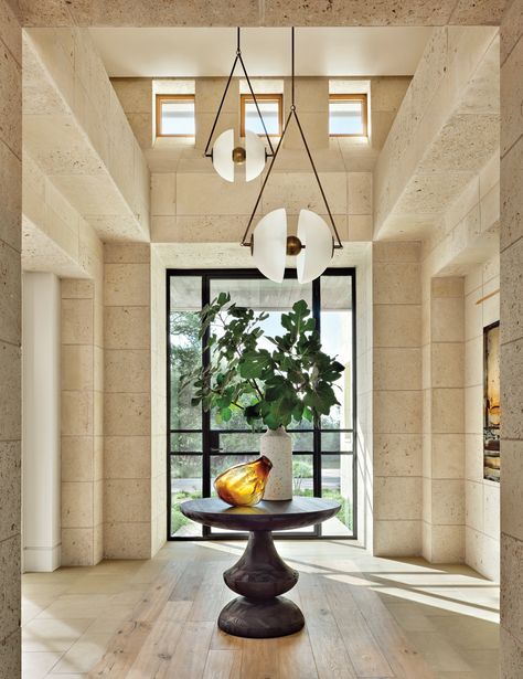 Drawing inspiration from the organic cream stone, the entry incorporates a caffè latte palette. An Emmemobili Birignao table sits underneath Apparatus’ Synapse pendants in aged and blackened brass. Luxe Magazine, Alfresco Area, Work Project, Landscape Construction, Austin Homes, Luxe Interiors, Prairie Style, Interiors Design, Entry Table