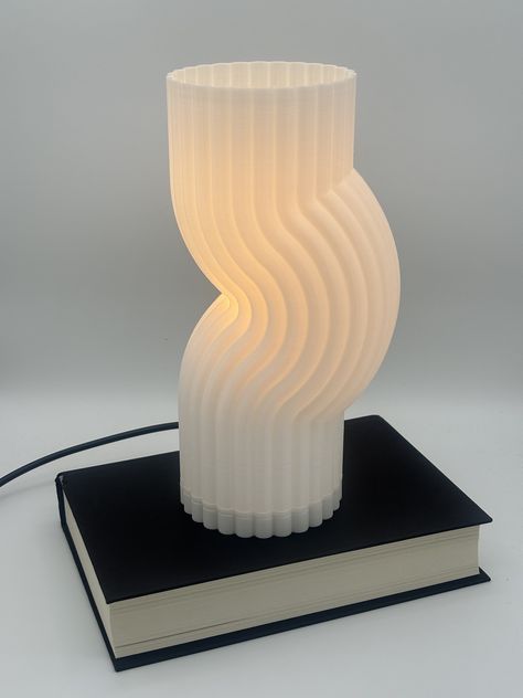 Discover the Bendy Lamp, a striking fusion of art and functionality, meticulously crafted through advanced 3D printing technology. This abstract lamp transcends traditional design with its fluid, organic shape, resembling a seamless bend in space and time. Perfectly at home in modern interiors seeking a touch of avant-garde elegance, each Bendy Lamp is a unique piece, showcasing the beauty of custom craftsmanship. Crafted from durable PLA plastic, this lamp emanates a soft, ambient glow, casting intriguing shadows that dance across any room. Whether as a focal point on a side table or as a conversation starter in your living space, the Bendy Lamp adds a distinctive flair to your decor. Available in a range of colors to suit your personal style, this piece promises to illuminate and inspire Avant Garde, Organic Lamp Design, 3d Printed Home Decor, Abstract Lamp, 3d Printed Lamp, 3d Print Design, Balloon Lamp, Lamp Inspiration, 3d Lamp