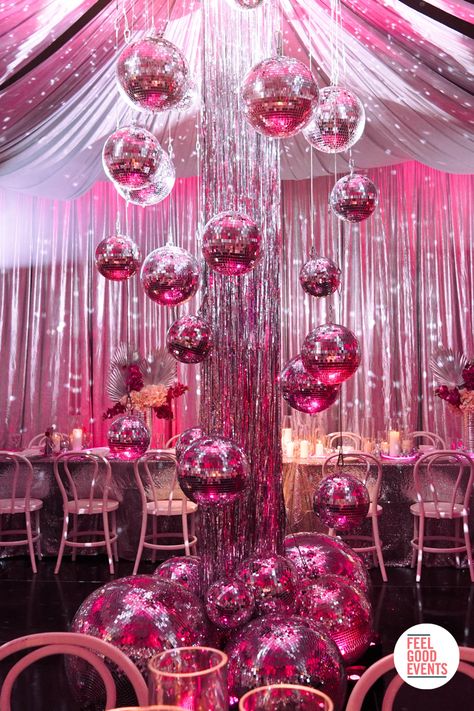 Pink disco themed dinner party. The photo features a mirror ball installation with pink mood lighting. In the background is a long table setup with florals and lighting. Pink Disco Decorations, Pink Dance Party, Pink Disco Ball Party, Pink Disco Party Decorations, Prom Ideas Decorations, Disco Dinner Party, Pink Disco Party, Metallic Party Decor, Party Mirror