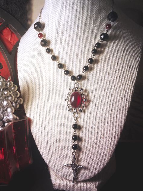 25 inch necklace with stainless steel chain and 3 1/2 inches of black and red glass beading on either side. Central pendant with red acrylic set and zinc alloy rose cross Made with love by Sacke & Sugar in Chattanooga, TN. Jewelry has small parts and is not intended for children. Follow us on Instagram for updates and sales: @sacke_and_sugar Goth Things To Buy, Cross Choker Gothic, Vampire Gothic Fashion, Calista Core, Goth Accessories Jewellery, Vampire Goth Fashion, Baddie Jewelry, Vamp Goth, Vampire Cosplay