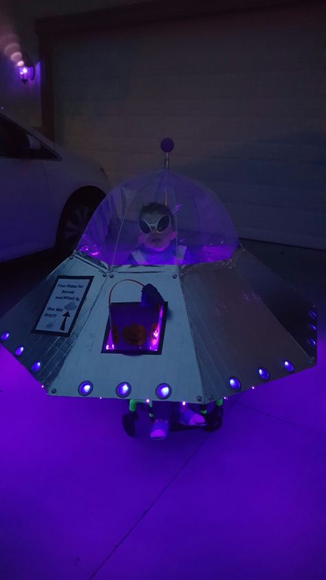 Cutest UFO wheelchair costume! Made with a dome umbrella, cardboard, duct tape, curtain grommets, large pearl stickers spray painted silver, battery operated lights, and wood dowels for support. Umbrella Spaceship, Outer Space Trunk Or Treat, Ufo Costume, Diy Alien Costume, Cardboard Spaceship, Wheelchair Costumes, Space Halloween, Alien Halloween Costume, Dome Umbrella