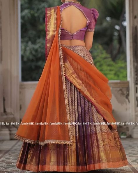 Do you need a beautiful and unique half saree for your next special occasion? Look no further than this lavender and orange Banarasi Silk lehenga! This gorgeous blouse features a collared V-neckline and puff sleeves with lace detailing on the yoke and sleeves, and the fabric used for it is golden tissue silk. The back of this dress is surely a head-to-turn pattern. It is paired with an organza silk-bordered dupatta. Whether you’re attending a wedding, a party, or a family occasion, this Banar... Golden Half Saree, Lavender Half Saree, Lavender And Orange, Trendy Outfits Indian, Outfits Indian, Gorgeous Blouses, Silk Lehenga, Half Saree, Do You Need