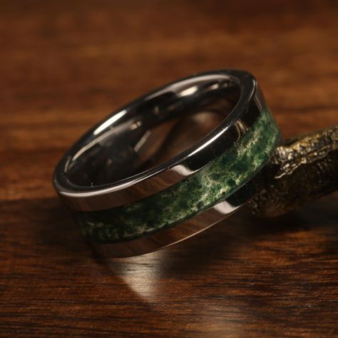 "Elevate your special moments with our stunning Green Moss Agate Tungsten Ring. This unique piece is not just a symbol of commitment but a statement of individuality and style. Crafted with high-quality black tungsten, this ring features a mesmerizing green moss agate inlay that showcases the beauty of nature. As a unisex ring, it offers versatility for both men and women seeking an extraordinary wedding band, anniversary token, or an engagement or promise ring. The black tungsten band provides Unique Mens Silver Rings, Nature, Moss Agate Engagement Ring For Men, Pretty Mens Wedding Rings, Mens Wedding Ring Green, Engagement Men's Ring, Forest Theme Wedding Ring, Mens Tungsten Rings, Male Engagement Ring Green