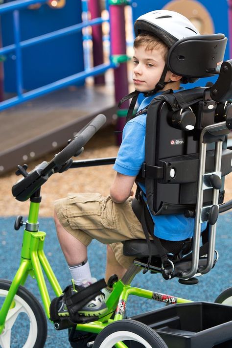 A boy wearing a helmet in a lime green Rifton Adaptive Tricycle Student Wellness, Adaptive Bikes, Gait Training, Gross Motor Activity, Pediatric Physical Therapy, Vision Therapy, Power Training, Muscular Endurance, Movement Activities