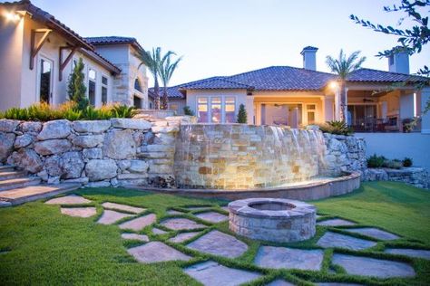 25 Sturdy Retaining Wall Ideas That Have Curb Appeal | HGTV Retaining Wall Waterfall, Ground Water Feature, Wall Waterfall, Contemporary Water Feature, Stone Water Features, Bohemian Patio, Concrete Retaining Walls, Sloped Yard, Outdoor Water Feature