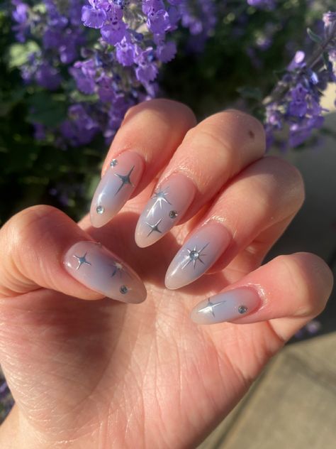 A light medium tanned left hand with almond shaped nails. The nails have a light baby blue ombré with silver star designs. Light Blue Star Nails, Blue Star Nails, Blue Gold Nails, Black Prom Nails, Cinderella Nails, Blue Prom Nails, Blue Chrome Nails, Blue And Silver Nails, Prom Nails Red