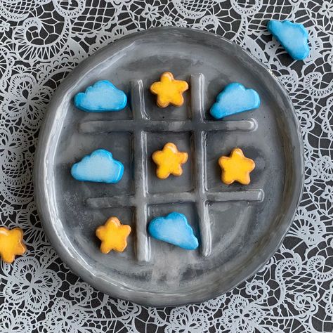 Elevate your game nights to a whole new level with our Handmade Full Moon and Stars Tic-Tac-Toe Board. This exceptional creation is more than just a game; it's a piece of art that beautifully combines celestial inspiration with craftsmanship. With its hand-painted full moon, starry X's, cloudy O's, and a glossy resin finish, this one-of-a-kind board is sure to capture hearts and create lasting memories. Board Features: 🌕 Full Moon Design: The game board takes the form of a radiant full moon, in Things To Make Of Clay, Air Dry Clay Board Game, Tiktaktoe Board Clay, Air Dry Tik Tak Toe, Clay Crafts Tic Tac Toe, Tiktaktoe Clay, Pizza Tic Tac Toe Clay, Air Dry Clay Ideas Tic Tac Toe, Air Dry Clay Checkers Board