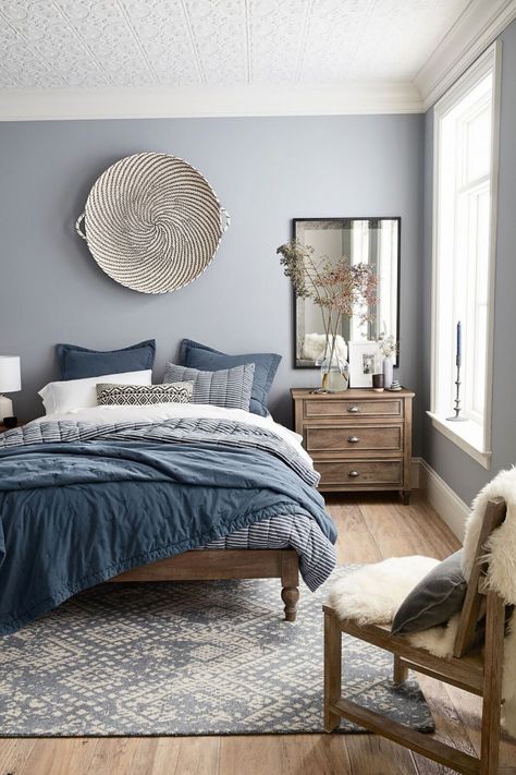 Modern bedroom design featuring a blue, gray, white and wood tone color scheme, a large woven basket as wall decor over the bed, layers of blue, gray, and white bedding, a large antiqued mirror over a wood bedside table, and a sheepskin throw on a wood chair - Home Decor & Decorating Ideas - mydomaine.com Design Ložnic, White Basket, Diy Wand, Grey Bedroom, Spare Bedroom, Bedroom Paint, Blue Bedroom, Main Bedroom, Beautiful Bedrooms