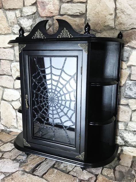 Beautiful vintage wooden wall cabinet with delicate details. The cabinet dates from the 70s and today enchants with its elegant black and an integrated spider web. It was painted completely black and coated several times with a clear varnish for protection. The accents of various varnishes, the antique fittings and the spider web handmade from a high-quality carbon film make "SIMPLY BLACK" a unique, hand-signed one-of-a-kind. Minimal deviations or small signs of wear are deliberately preserved b Goth Cabinets, Gothic Tiny House, Gothic Furniture Dressers, Gothic Display Cabinet, Small Room Storage, Gothic Curio Cabinet, Gothic Furniture Storage Cabinets, Black Display Cabinet, Wooden Display Cabinets