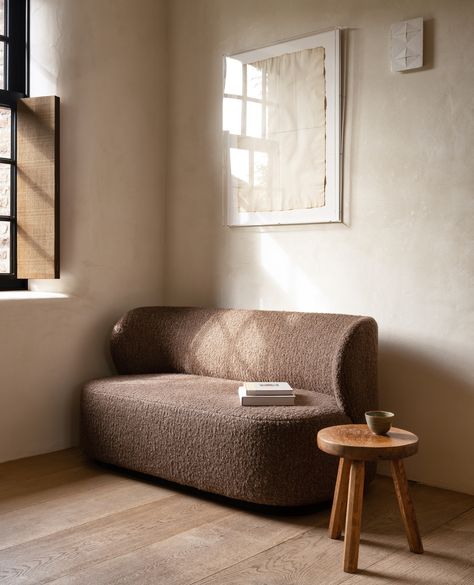 A brown loveseat upholstered with bouclé fabric by Collett & Victor and a small wooden side table Brown Boucle Sofa, Curved Loveseat, Organic Sofa, Peaceful Moments, Bed Bench, Curved Back, Organic Shapes, Love Seat, Dining Bench