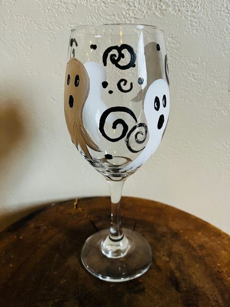 This is a painted Ghostly Halloween wine glass. I used acrylic painted and baked them so that the paint is set so they can be put in the washer but I would always recommend hand washing wine glasses whether painted or not. I love Halloween and I just thought that these would be a cute way to celebrate the holiday. Wine Glass Halloween Crafts, How To Paint Wine Glasses, Halloween Wine Glass Painting, Halloween Wine Glasses Diy, Halloween Painted Wine Glasses, Fall Painted Wine Glasses, Spooky Wine Glass Painting, Ghost Wine Glasses, Hand Painted Halloween Wine Glasses