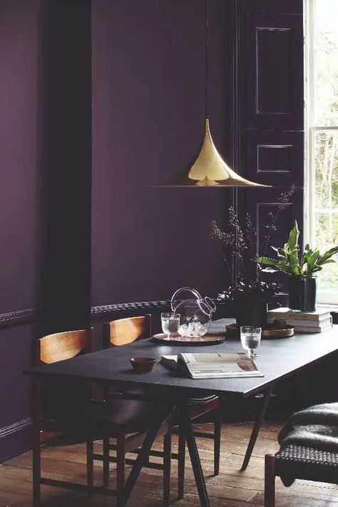 a moody dining room with a deep purple accent wall, a black trestle table and wooden chairs, a shiny gilded pendant lamp Purple Accent Wall, Purple Accent Walls, Deco Violet, Purple Dining Room, Purple Living Room, Dining Room Paint Colors, Dining Room Paint, Purple Rooms, Black Living Room