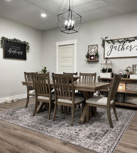 Stained wood X base dining table is lit by a black lantern pendant light in this farmhouse dining room with gray walls. The table is accompanied by matching stained wood dining chairs with white seat cushions. Dining Rooms With Farmhouse Chandeliers, Modern Rustic Home Decor Ideas, Dinning Room Modern Farmhouse Decor, Dining Room With Grey Walls, Black Farmhouse Kitchen Decor, All White Home Decor, Dining Room Themes, How To Decorate A Dining Room Wall, Small Kitchen Theme Ideas