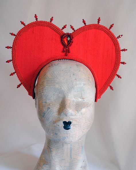 This striking headdress will take any Queen themed costume to another level! Queen of Hearts to Evil Queen, you will certainly won't pass unnoticed! The heart shape of this headpiece frames the face ever so elegantly giving the illusion of a heart. This piece is covered with silk shantung.It is embellished with crystals all around for that so in-fashion halo effect, as well as a beautiful inverted tear-drop focal element and finished off with braided trimming. Choose between red (pictured) or bl Queen Of Hearts Aesthetic, Heart Headpiece, Queen Of Hearts Cosplay, Alice In Wonderland Halloween Costume, Valentine Costume, Lions Face, Alice In Wonderland Halloween, Queen Of Hearts Halloween, Evil Princess