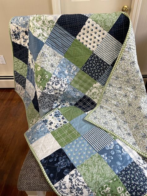 This handmade quilt is ready to snuggle your little one. This quilt features a patchwork pattern in shades of blue, green and white. There are coordinating prints on the front of this darling quilt. The backing is done in a small blue floral print which brings in all the colors of the front of the quilt. This quilt is sure to be a keepsake. The quilting is done in a cross hatch design. The binding is double folded for durability. The binding is done in a green gingham and is attached by machine for added sturdiness. The dimensions of the quilt are 36" wide by 44 1/2" long. As with all handmade quilts, please launder on a gentle setting in cool water and tumble dry on low. Through the laundering process the quilt will begin to show some puckering which is usual and expected. This will give Four Color Quilt Patterns, Large Quilt Patterns, Baby Boy Blanket Quilt, Blue Green Quilt, Blue And Green Quilt Ideas, Blue And White Quilts Patterns, Quilt Color Combinations, Aesthetic Quilts, Green Quilts Ideas