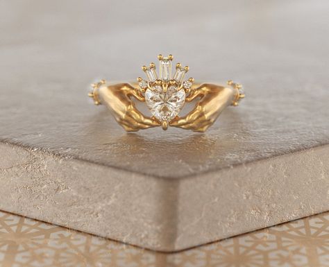 This exquisite Claddagh ring features a sparkling Moissanite heart (approx. 0.5ct), cradled by a crown of baguette diamonds (total carat weight approx. 0.55ct).  Made in your choice of 10K, 14K, or 18K Rose, Yellow, or White gold, or Platinum.  The classic design symbolizes love, friendship, and loyalty, making it a timeless heirloom.  Customize your heart stone!  Please allow 2-3 weeks for production. Sizes up to 8 included, contact us for larger sizes.