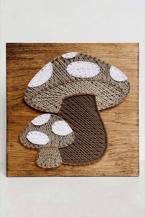 A large and small mushroom made in string art using dark and light brown tone string on a piece of stained wood. Nail And Yarn Art Designs, Mail And Thread Art, Wooden String Art, Highland Cow String Art, Mushroom String Art, Boho String Art, String Crafts Ideas, Nail String Art Patterns, Thread Art On Wood