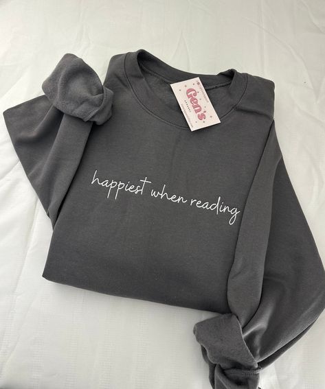 Embrace your reading bliss with our "Happiest When Reading" embroidered sweatshirt, tailored for the true book lover. This minimalist book sweatshirt, an ideal book club gift, effortlessly combines comfort and literary charm, ensuring you stay stylishly cozy during your favorite reading sessions. Color in example is Charcoal Grey * 50% cotton, 50% polyester * Pre-shrunk * Classic fit * 1x1 athletic rib knit collar with spandex * Air-jet spun yarn with a soft feel and reduced pilling * Double-nee Bookish Sweatshirts, Minimalist Book, Bookclub Gifts, Lover Sweatshirt, Embroidered Sweatshirt, Embroidered Sweatshirts, Book Lovers Gifts, Book Lover, Charcoal Grey