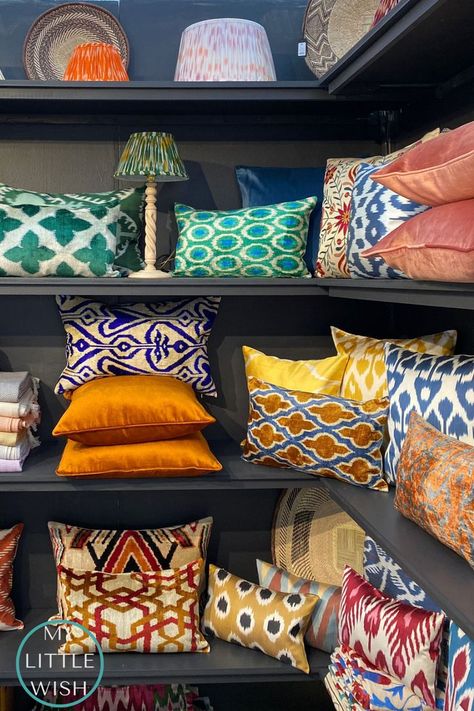 Image of a shelf of colourful jewel tone Ikat velvet and silk cushions with lampshades and other decorative items also displayed. Booth Display Ideas Diy, Fall Dining Room Table, Fall Dining Room, Loft Room, Go Crazy, Decor Essentials, Home Textiles, House Interior Decor, Pillows And Throws