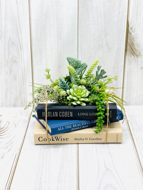 "Total Design Dimensions- 10.5\" W x 8.5\" D x 10\" T Stacked 3 reclaimed books used as a faux Succulent table, library or desk centerpiece. The faux Succulents are in set to the top book using a variety of faux Succulents, a Cactus, Ming Pine, Hops, Donkey Tail, mini Echeveria, Spike Succulent and Agave Spike, and String of Pearls. This piece is designed on all sides so the beauty can be seen from any angle. No green thumb needed as this is faux but oh so real looking. Perfect for a home librar Succulent Lantern Centerpiece, House Plant Wedding Decor, Table Decor With Books, Summer Centerpieces For Home, Centerpiece Ideas For Dining Room Table, Plants As Centerpieces, Table Centerpieces Flowers, Home Plants Decor, Corporate Centerpieces