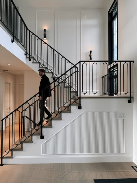 Ornate black steel railing on a grand staircase in front of white walls. Staircase Design Metal, Staircase Design Modern Railing Ideas, Custom Stair Railing, Traditional Modern Staircase, Staircase Design With Landing, Updated Stairwell, Transitional Stair Railing, Black Metal Spindles Staircase, Modern Metal Stair Railing